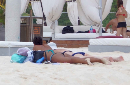 One dark woman and one white woman tanning on the beach in Playa Del Carmen.