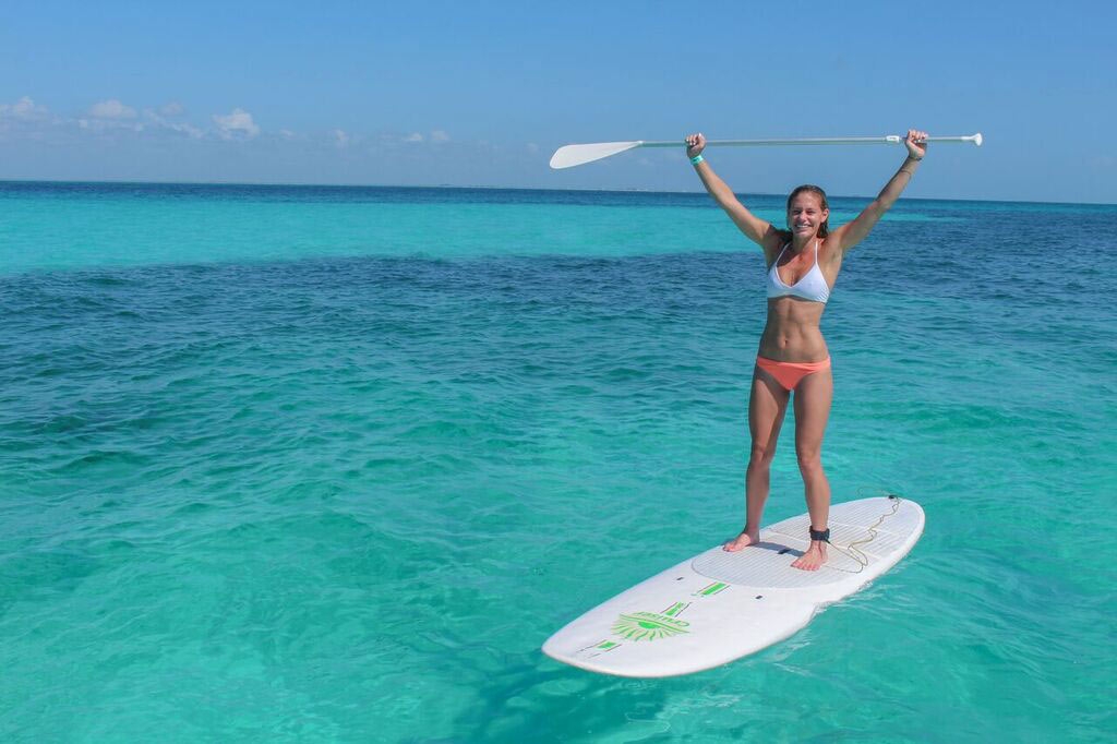 woman-standing-on-a-paddleboard-with-her-arms-outstretched-during-a-playa-del-carmen-booze-cruise