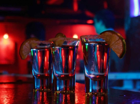 Three shots of tequila on a bar.
