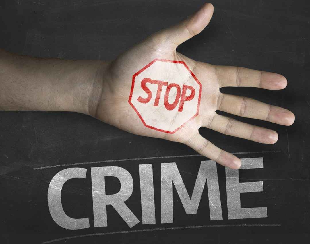 A hand and chalkboard that reads, stop crime.