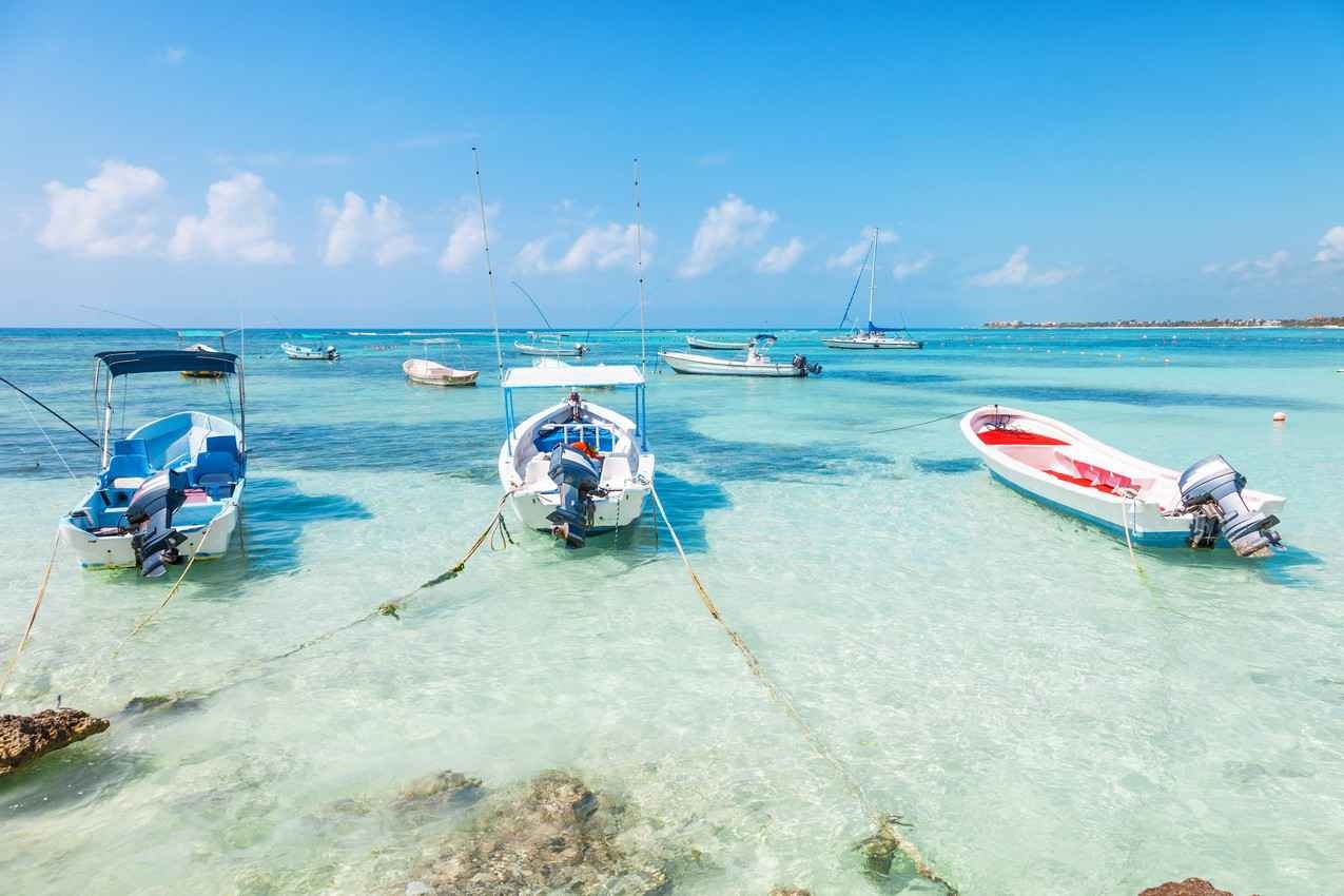 A group of several fishing boats anchored just off the shore in Playa Del Carmen.