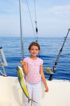 A young girl is holding up a fish that she caught.
