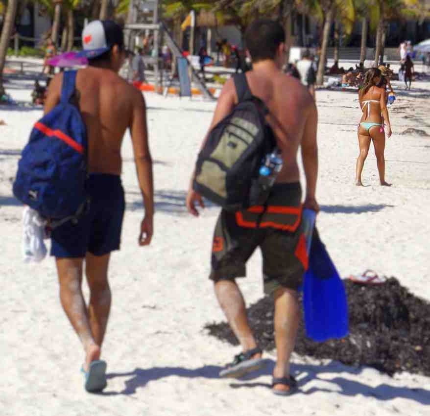 Two men staring at a hot woman walking on the beach.