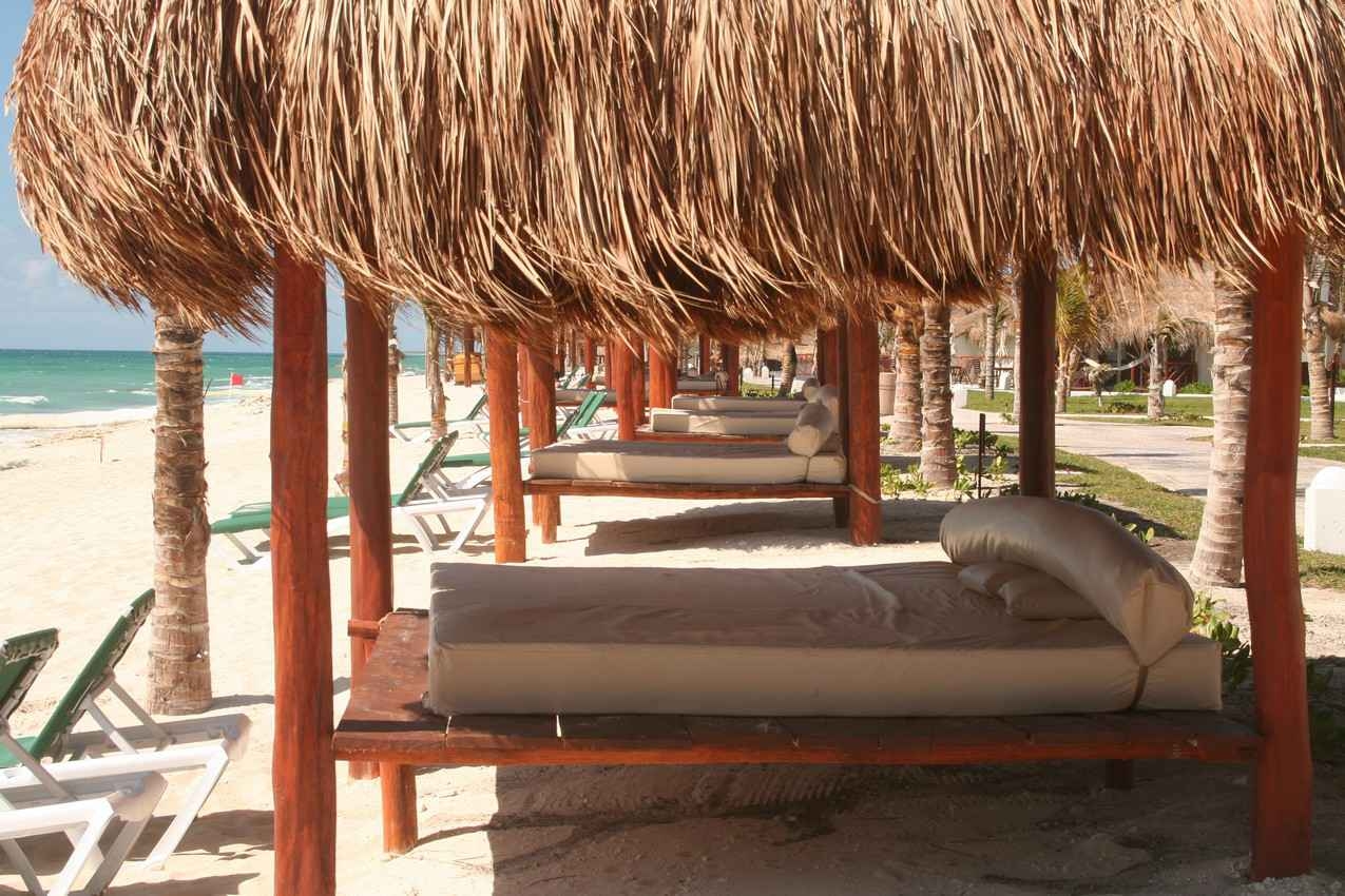 A row of parental beds with palapas overhead on the beach in Playa Del Carmen.