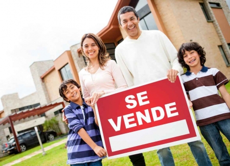 A family holding a for sale sign written in Spanish.