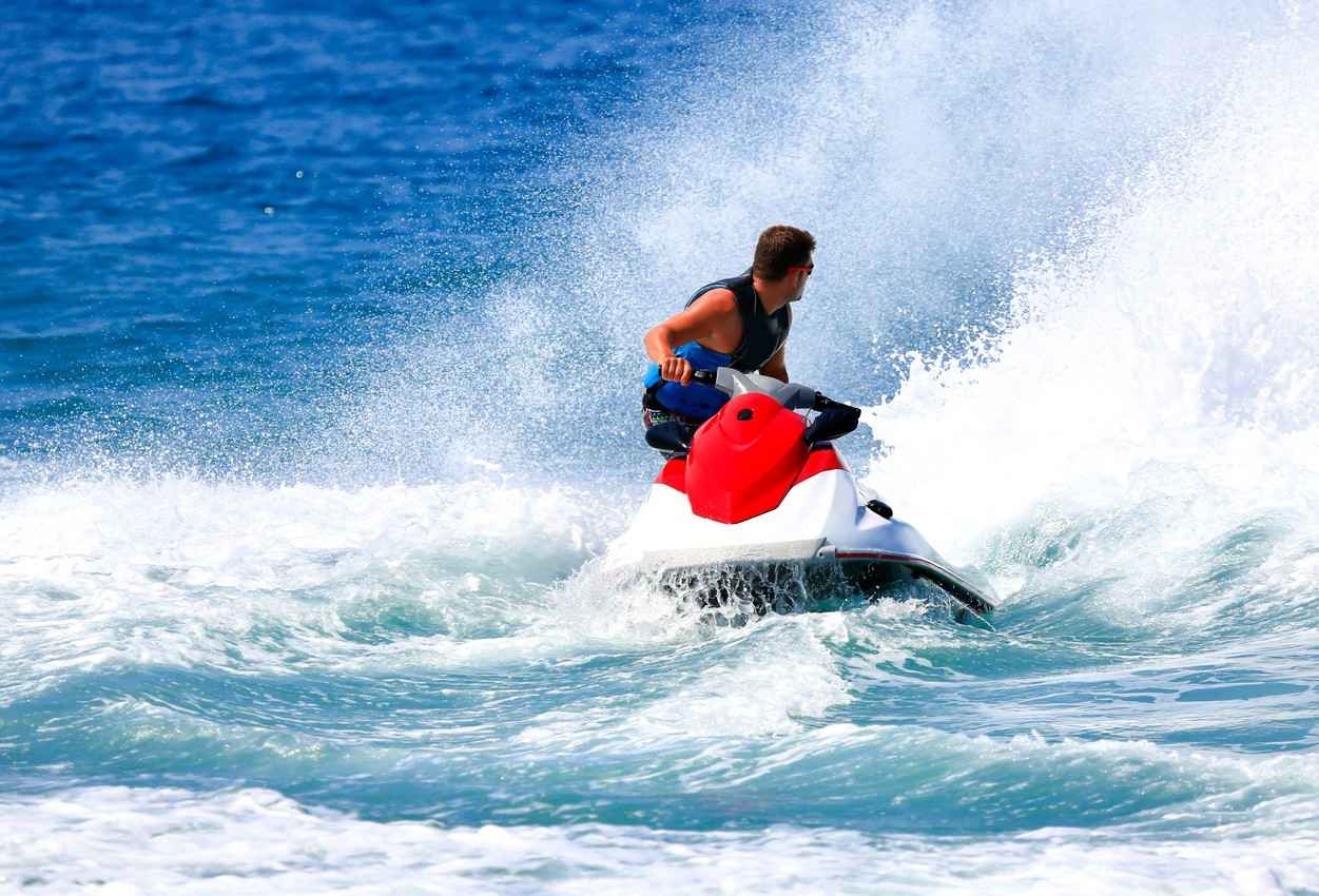 A man looking backwards while riding a jet ski.