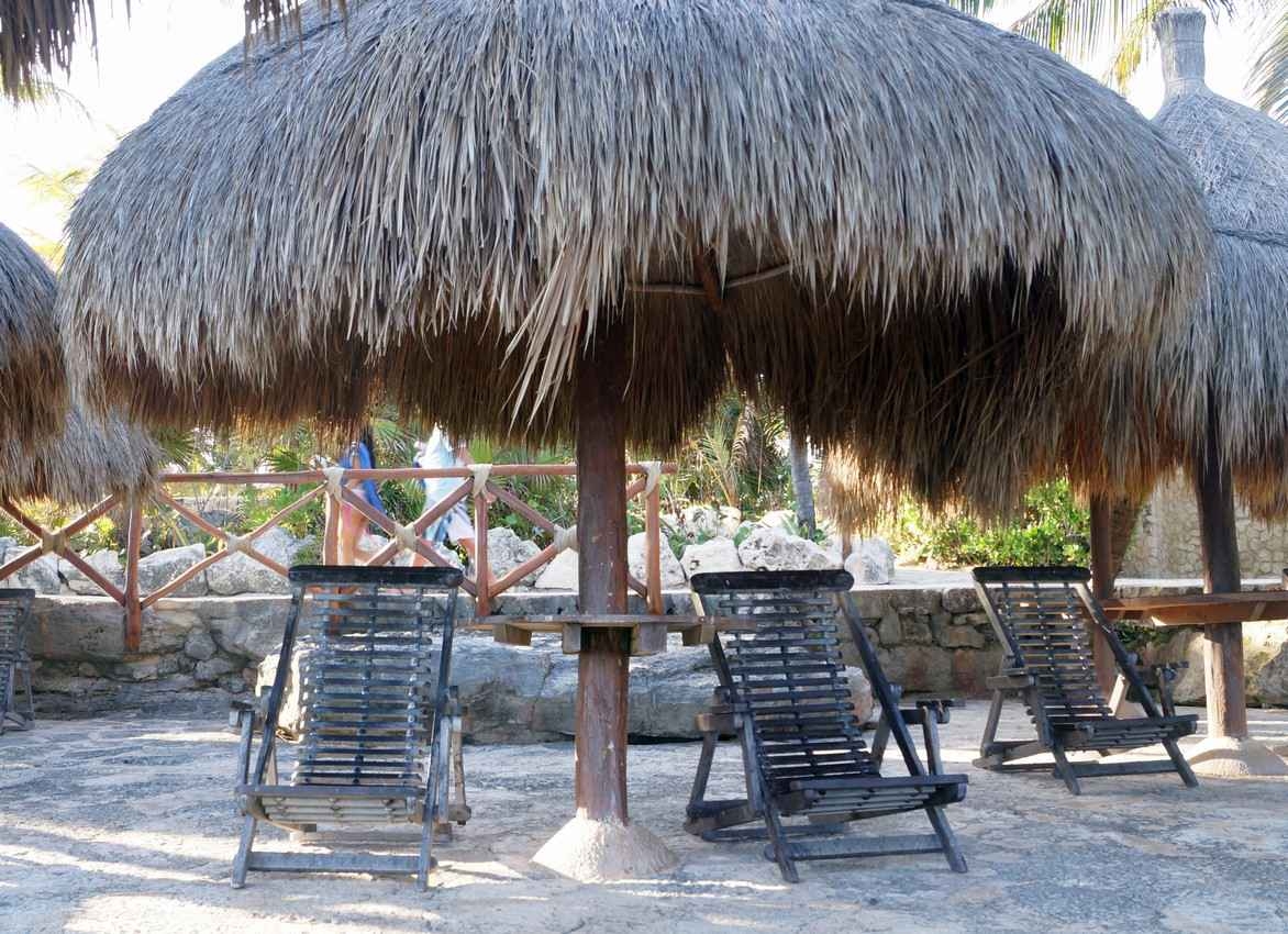 A palapa with two lounge chairs underneath it.