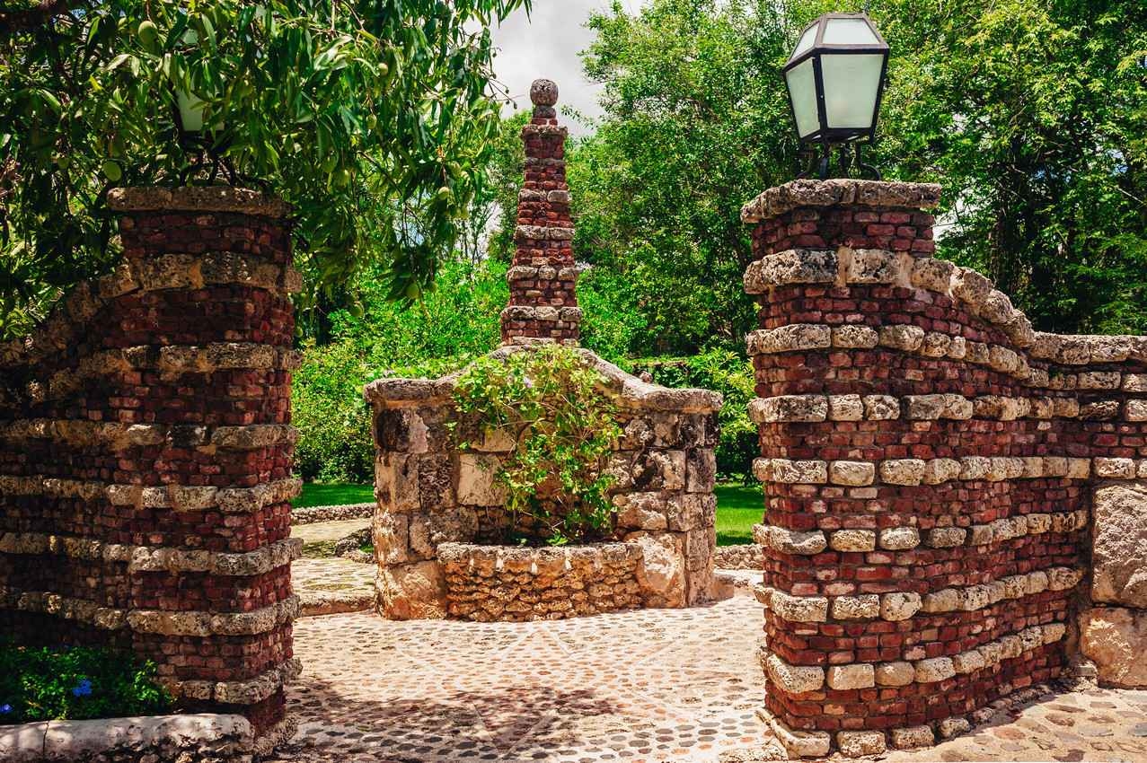 A beautiful brick entrance featuring a water fountain on some expensive property.