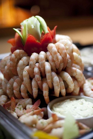 A shrimp cocktail dish with delicately cut vegetables and dip.