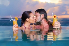 A man and a woman making out in a beachside pool.