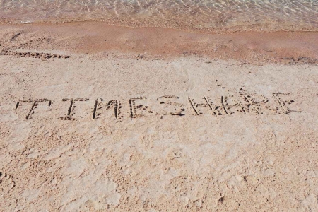 The word TIMESHARE written in sand on a Mexican beach.