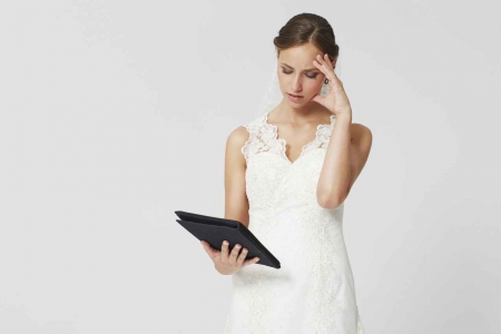 A woman in a bridesmaid dress looking at a notebook of wedding tasks to do.