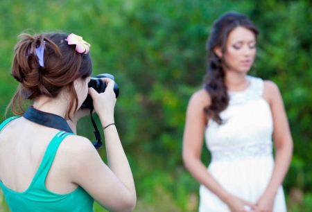 A female wedding photographer taking beautiful pictures of a bride with a jungle in the background.