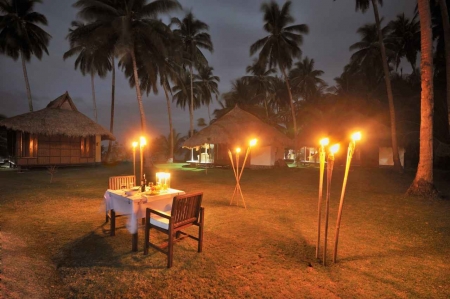 A romantic candlelit dinner with a table and tiki torches.