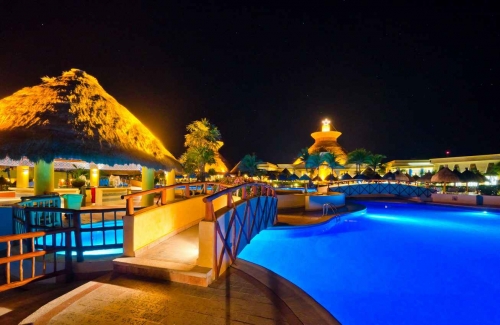 A swimming pool at night with many lights in an all-inclusive resort.