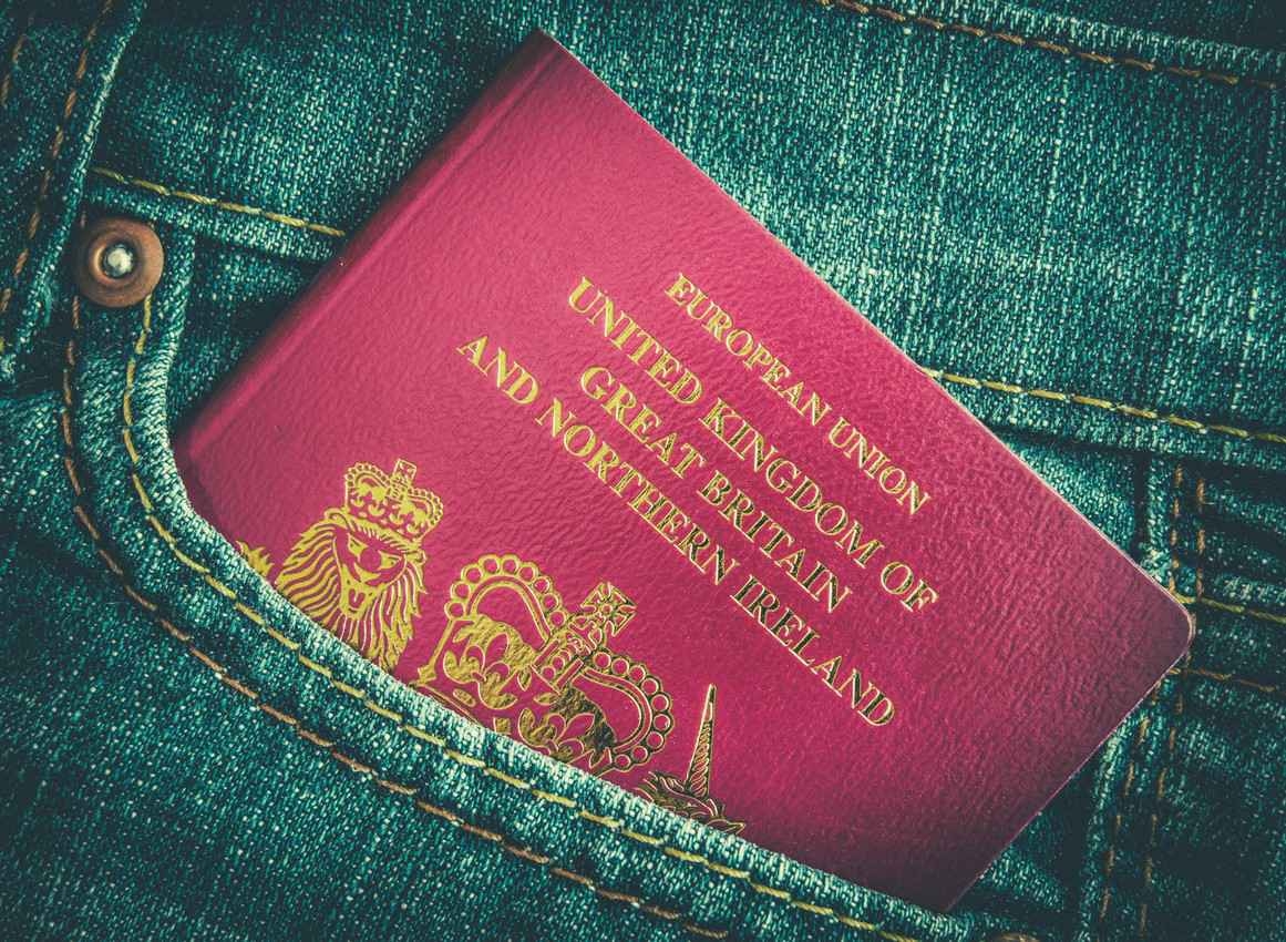A United Kingdom passport in the back pocket of someone's jeans.