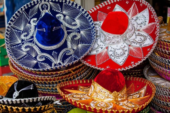 Several stacks of sombreros for sale on the street.