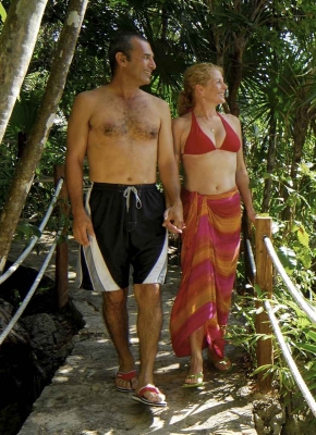 A hot woman in a bikini and a man in swimming shorts taking a romantic walk in the jungle.