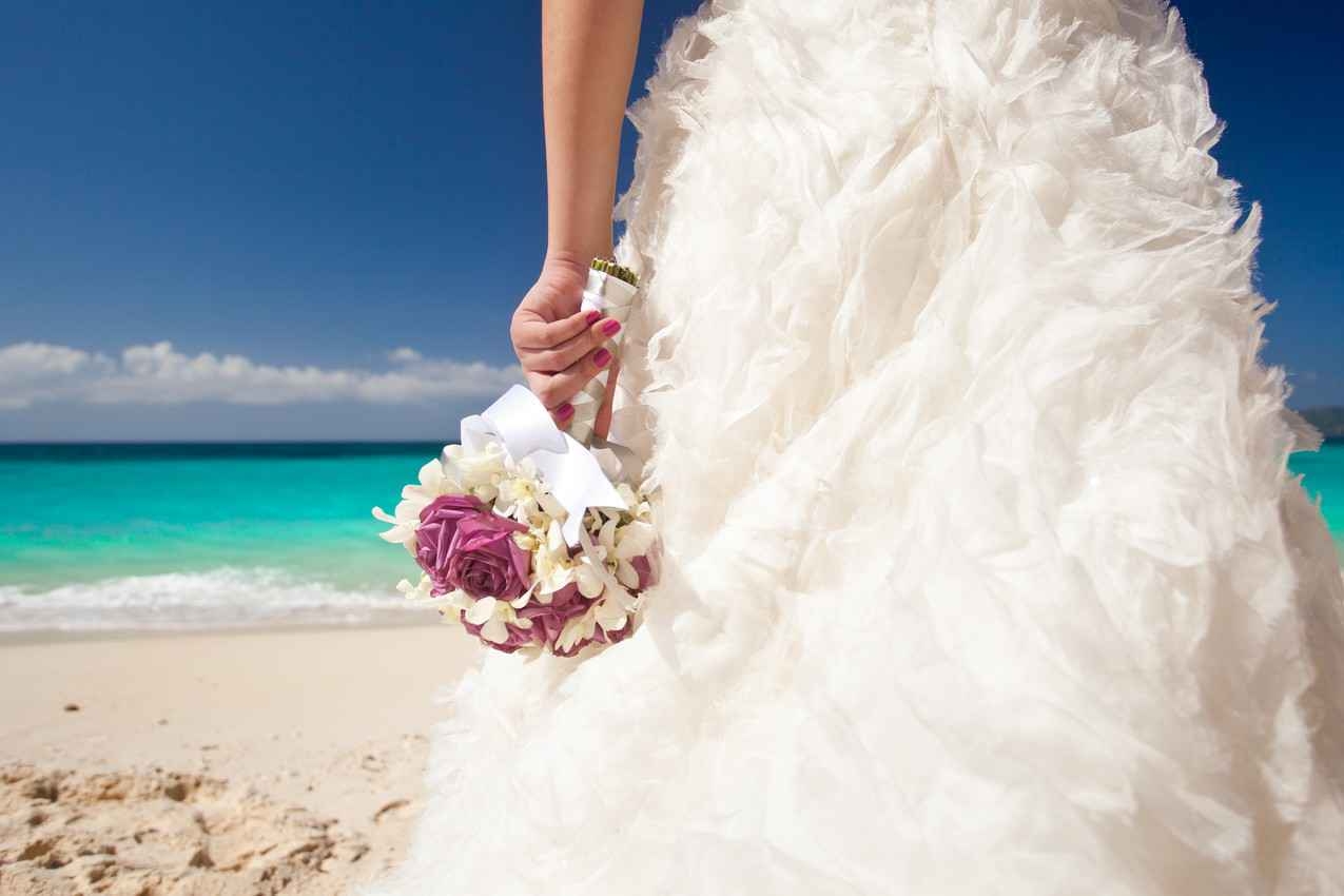A beautiful wedding dress and bouquet of flowers on the beach in Playa Del Carmen.