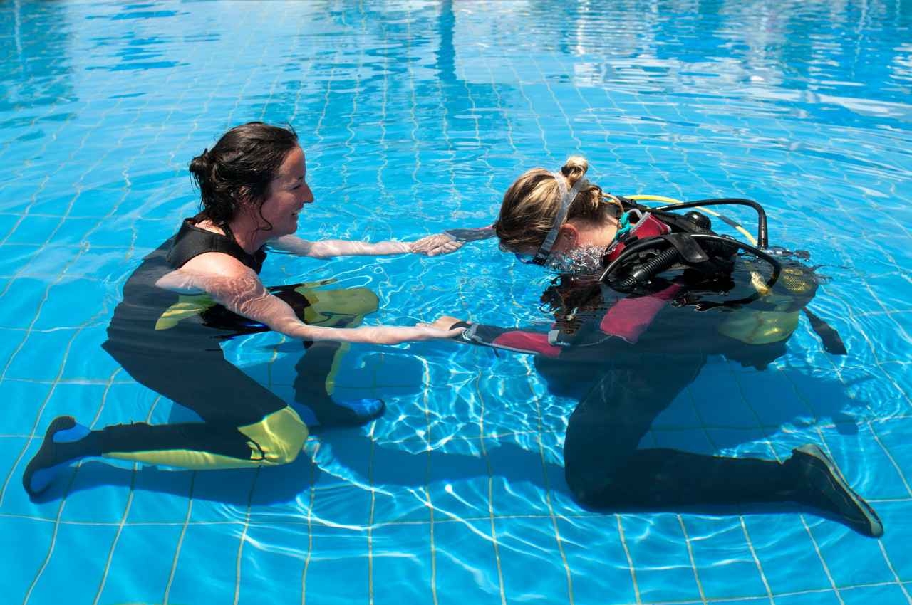 A female scuba diving instructor was working with a female student in a large swimming pool.