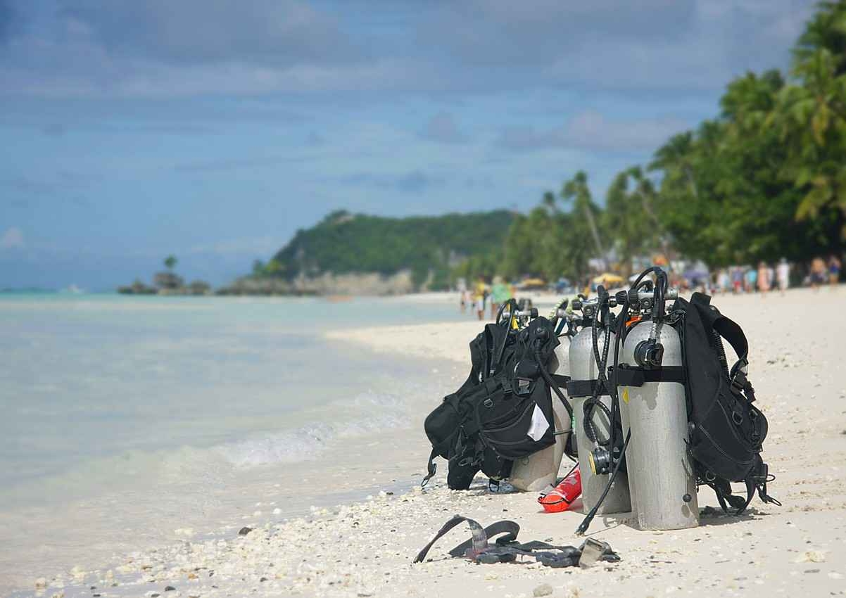 Several scuba diving tanks and an array of equipment on a beach near the Tulum ruins.