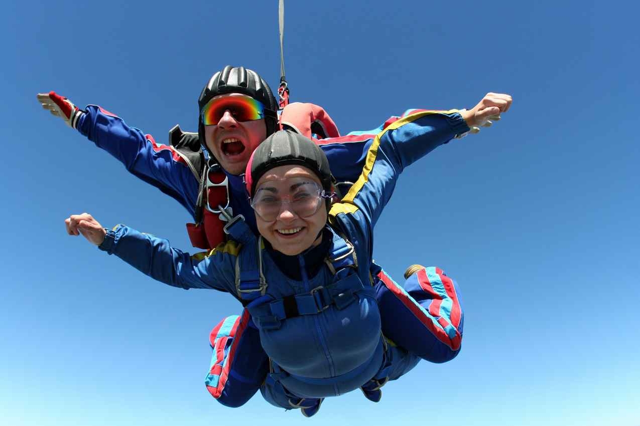 A woman and a skydiving instructor doing a tandem jump.