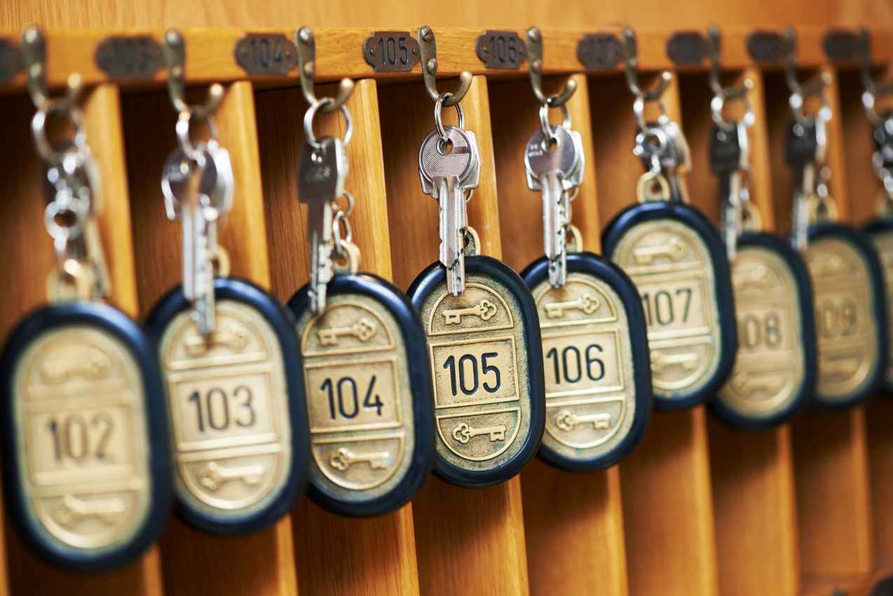 A group of numbered room keys hanging from a desk at a reception area.