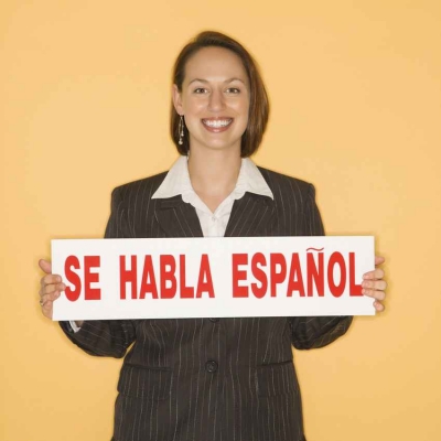 A Spanish teacher holding a sign that says, SE HABLA ESPANOL.