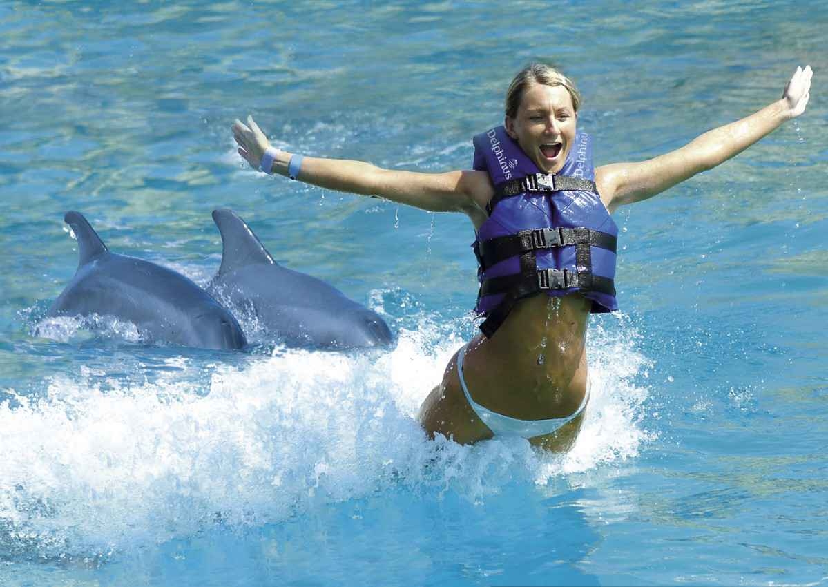 A young woman is lifted in the air while she is being pushed by two dolphins.
