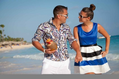 een man en een vrouw die hand in hand over het strand lopen.