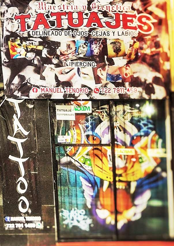 The door of a tattoo shop in Playa Del Carmen with lots of artwork on it.