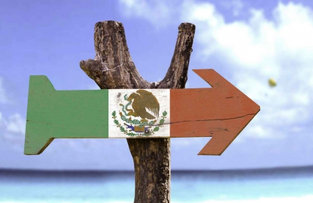 A Mexican flag arrow sign in front of the Caribbean Sea.