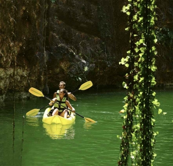 Several tourists riding a kayak near a cenote.