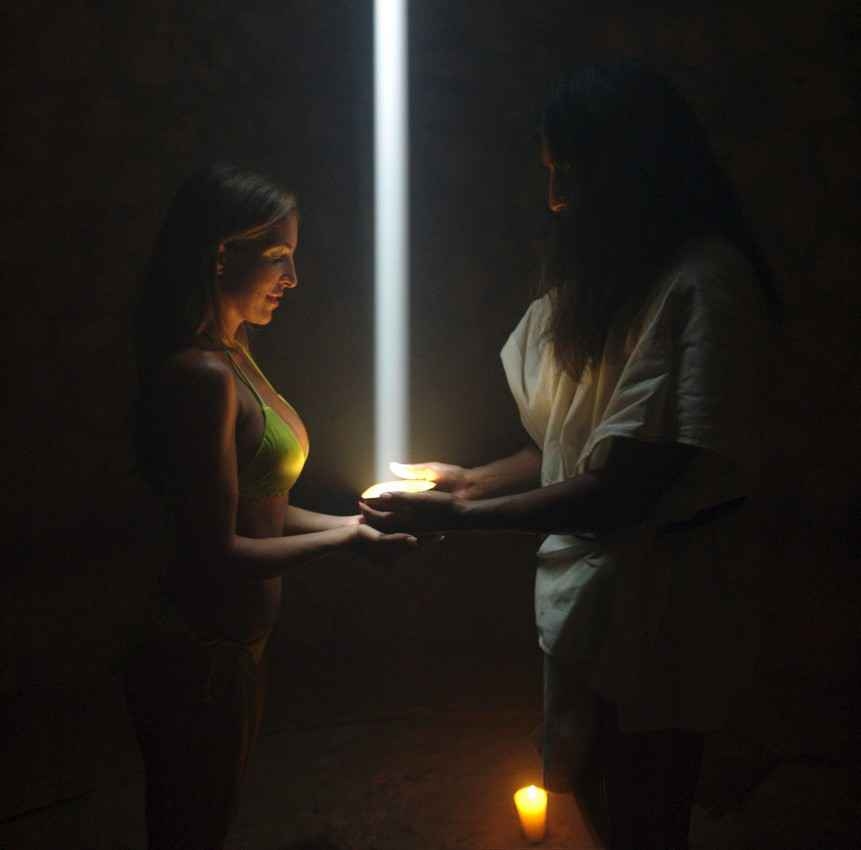 A Mayan rejuvenation ceremony being performed on a sexy female tourist in a bikini.